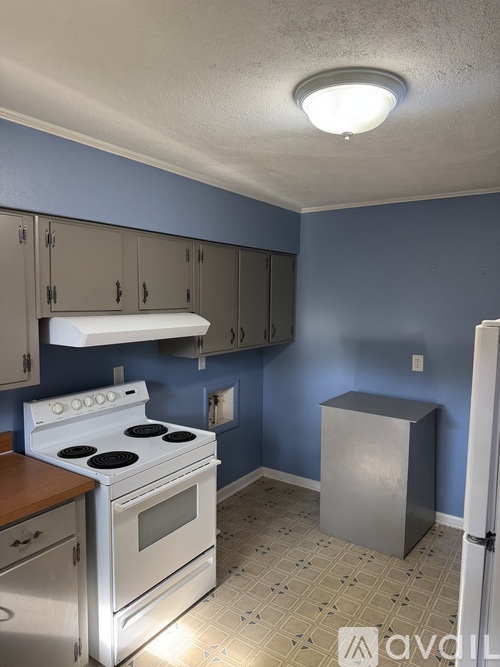 A kitchen with a white stove and blue walls.