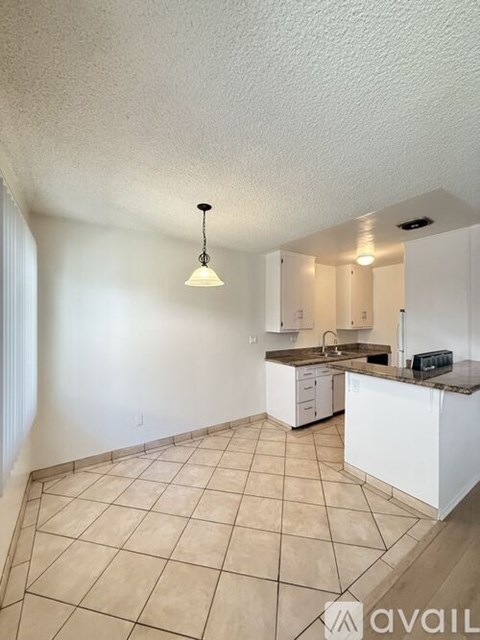 A kitchen with white cabinets and a tiled floor.