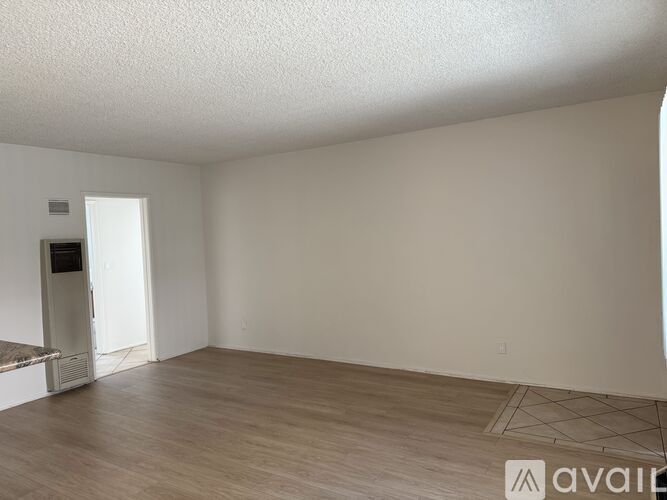 A spacious room with wooden flooring and a white ceiling.