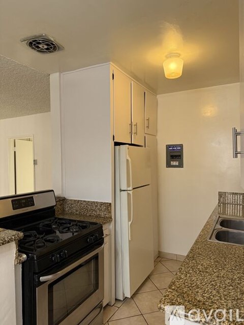 A kitchen with a black stove top oven and a white refrigerator.