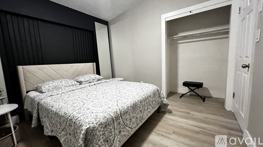 A bedroom with a bed, a small table, and a chair.