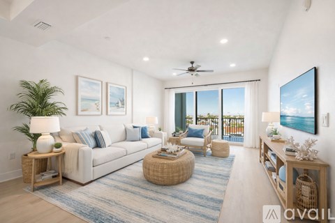 A living room with a white couch, a blue rug, and a painting of a beach scene on the wall.