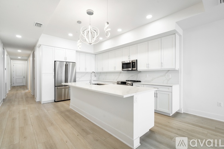 A modern kitchen with white cabinets and a wooden floor.