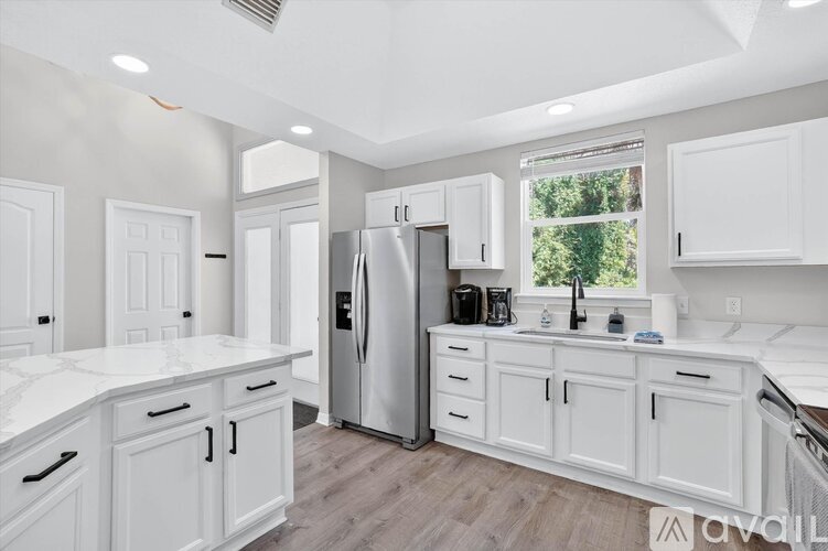 A kitchen with white cabinets and a stainless steel refrigerator.