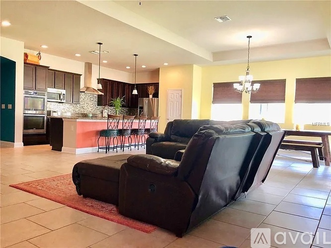 A living room with a black couch and a red rug.