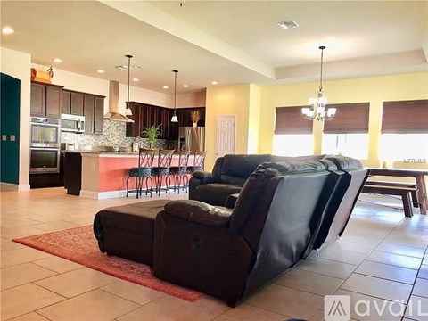 A living room with a black couch and a red rug.