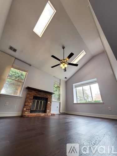 A living room with a fireplace and a ceiling fan.