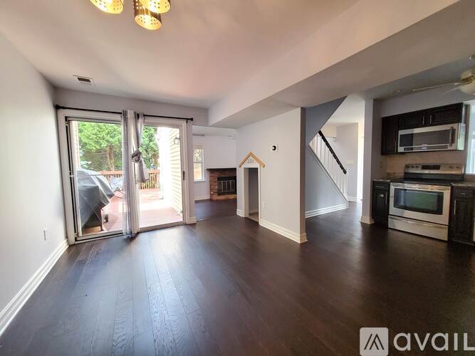 A spacious living room with hardwood floors and a kitchen area in the background.