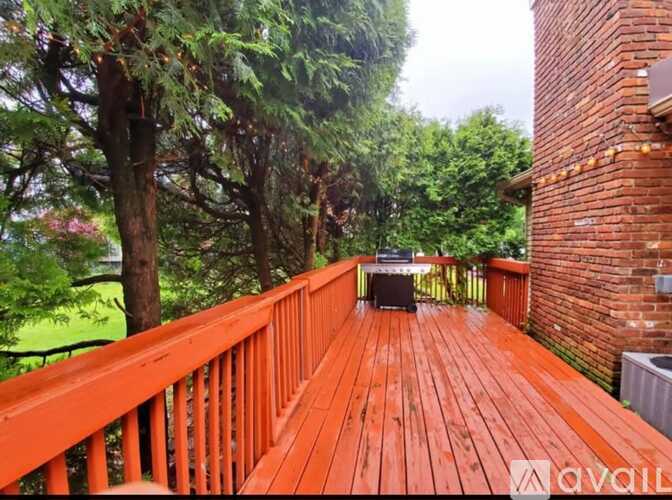 A wooden deck with a railing and a table surrounded by trees.