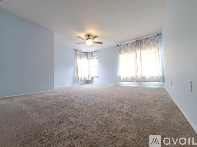 A spacious room with a carpeted floor and a ceiling fan.