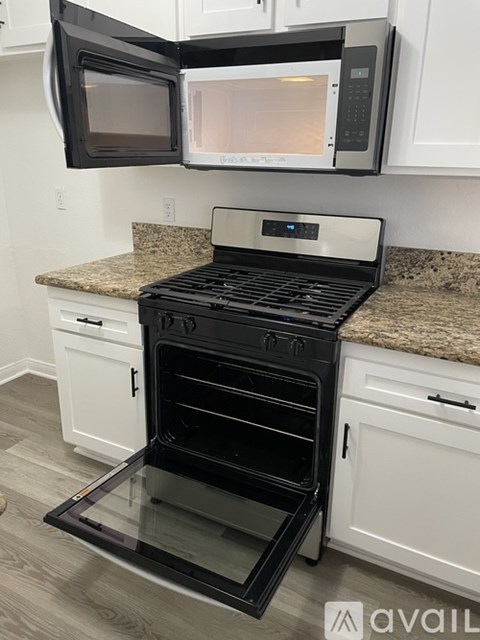 A black oven with a glass door is in a kitchen with white cabinets.