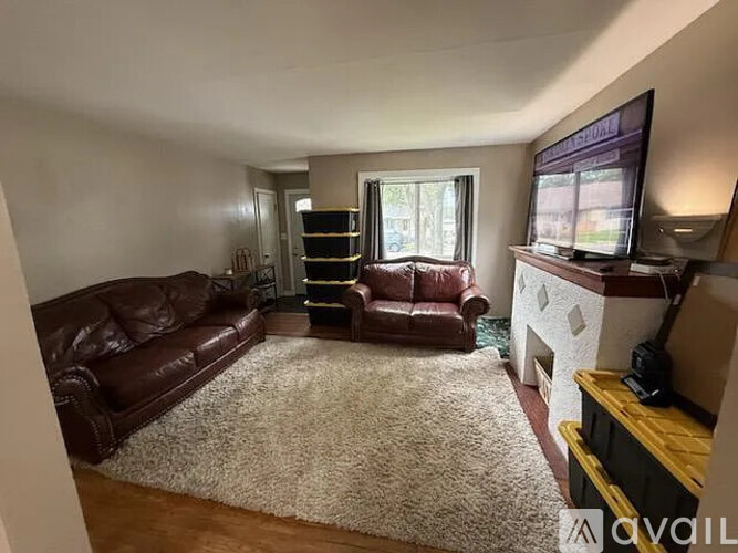 A living room with a brown leather couch and a white rug.