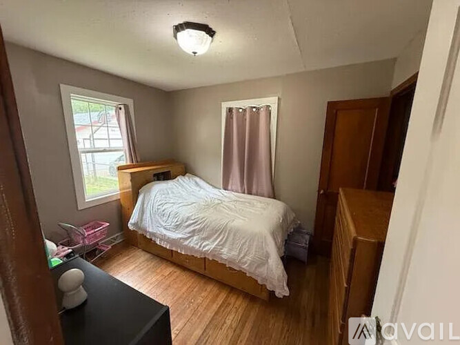 A bedroom with a bed, nightstand, and window.