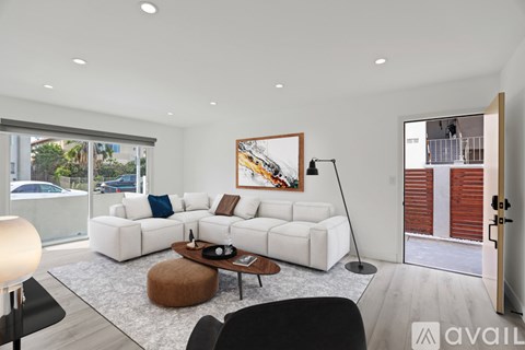 A living room with a white sofa and a painting on the wall.