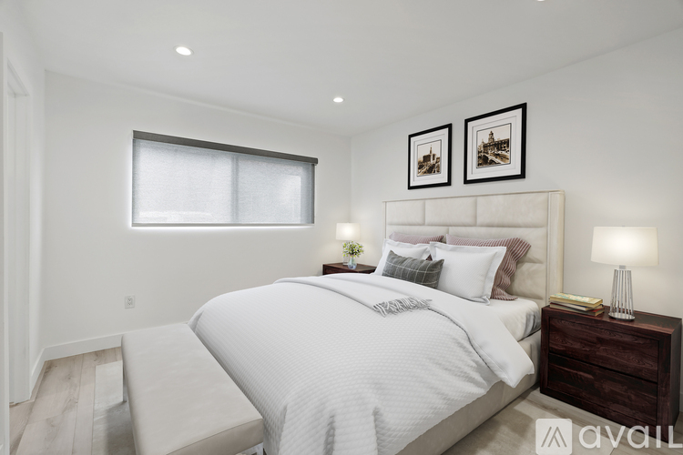 A bedroom with a large bed and two pictures on the wall.