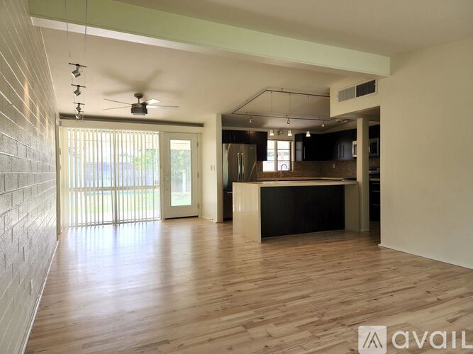 A spacious room with wooden floors and a ceiling fan.