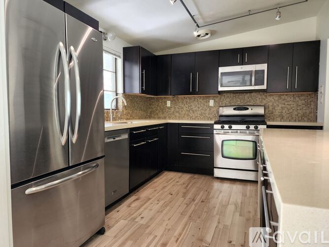 A modern kitchen with a stainless steel refrigerator and black cabinets.