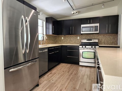 A modern kitchen with a stainless steel refrigerator and black cabinets.