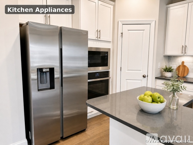 A modern kitchen with a stainless steel refrigerator and a bowl of green apples on the counter.