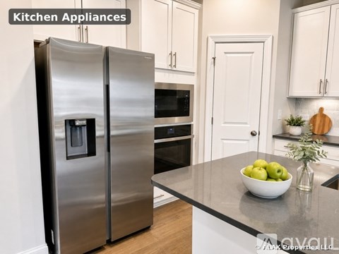 A modern kitchen with a stainless steel refrigerator and a bowl of green apples on the counter.