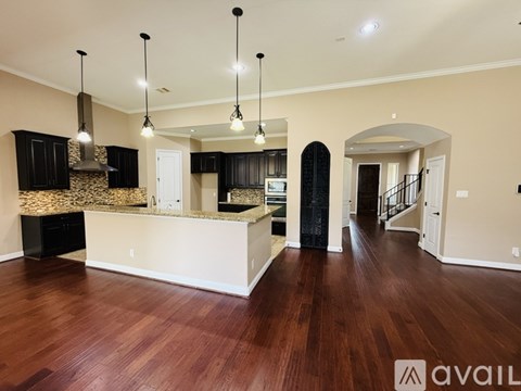 A spacious kitchen with dark wood cabinets and a white island.