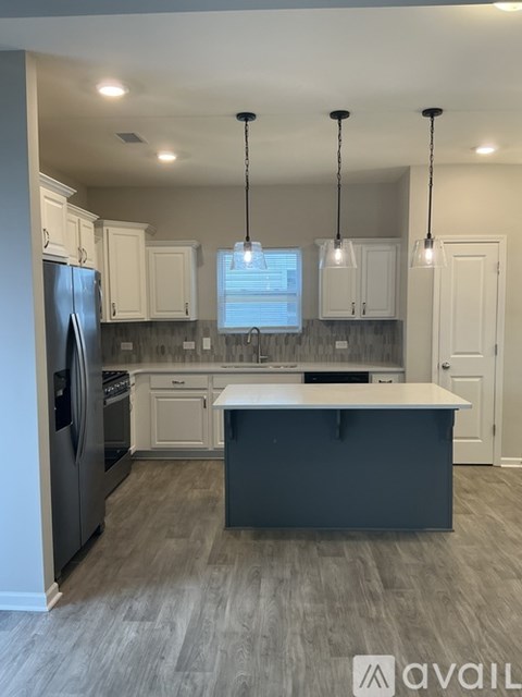 A kitchen with a black island in the middle.