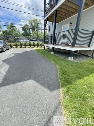 A concrete pathway leads to a building with a balcony.