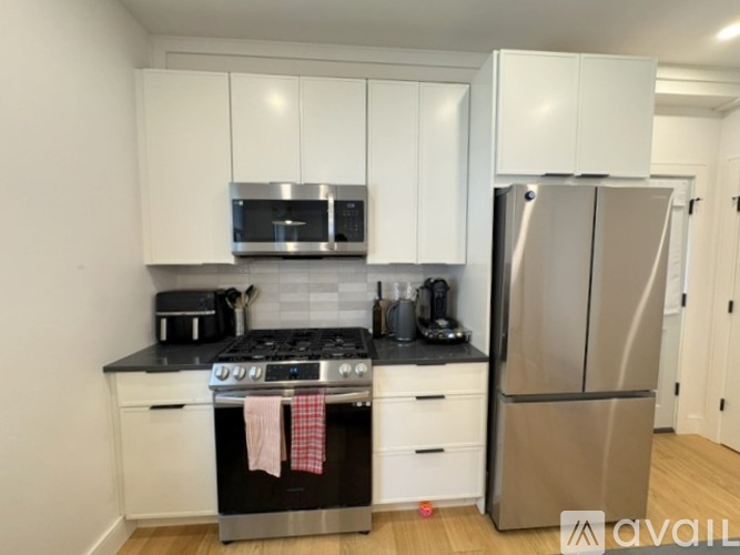 A kitchen with white cabinets and a black countertop.