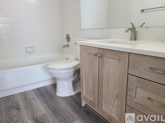 A white toilet sits next to a bathtub in a bathroom with wooden cabinets.