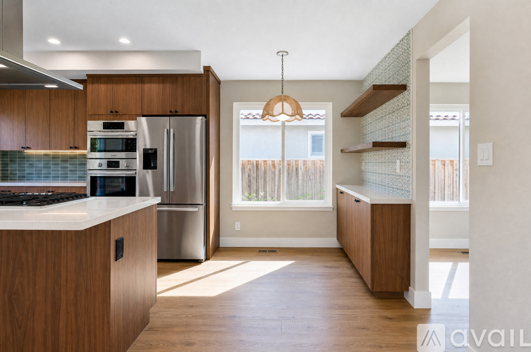 A modern kitchen with wooden cabinets and a stainless steel refrigerator.