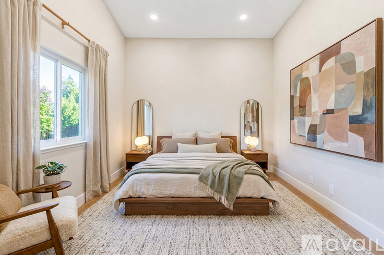 A bedroom with a large bed, two lamps, and a painting on the wall.