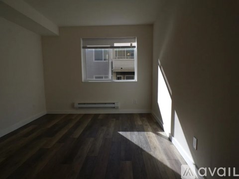 A room with wooden floors and a window showing a view of a building outside.