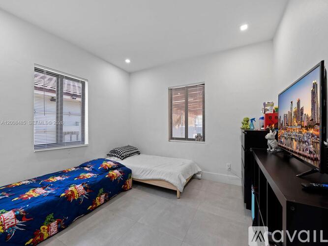 A bedroom with a bed, a television, and a window.