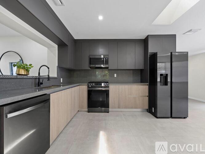A modern kitchen with dark grey cabinets and stainless steel appliances.