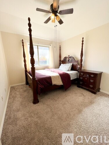 A bedroom with a four poster bed and a ceiling fan.