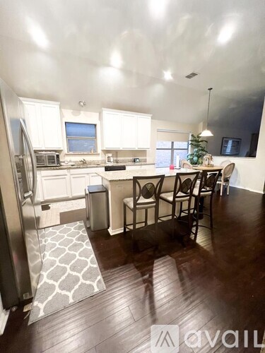 A kitchen with white cabinets and a wooden floor.