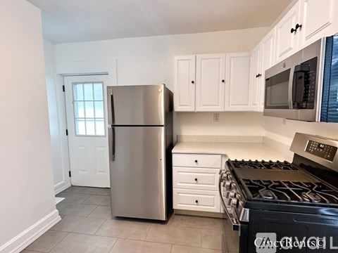 A kitchen with white cabinets and a stainless steel refrigerator.
