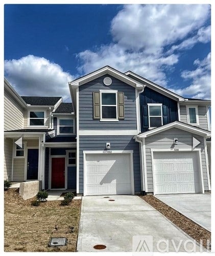 A two-story house with a garage door and a red door.