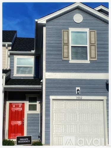 A two-story house with a red door and a garage door.