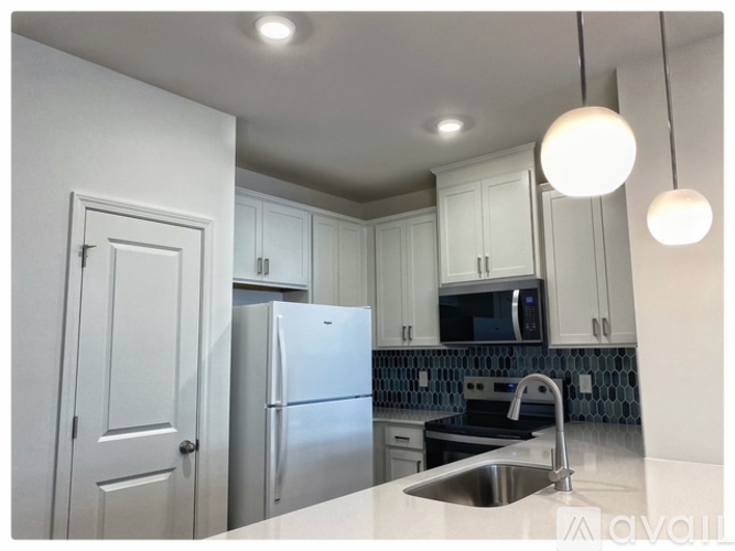 A kitchen with white cabinets and a stainless steel refrigerator.