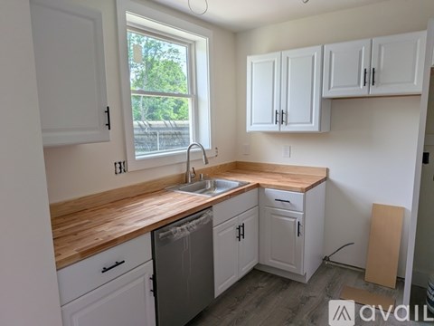 A kitchen with white cabinets and a wooden counter top.