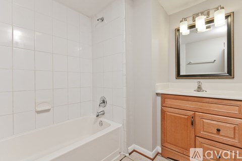 A bathroom with a white tub, sink, and mirror.