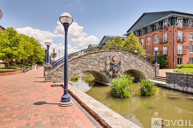 A stone bridge with a clock on it crosses a body of water.