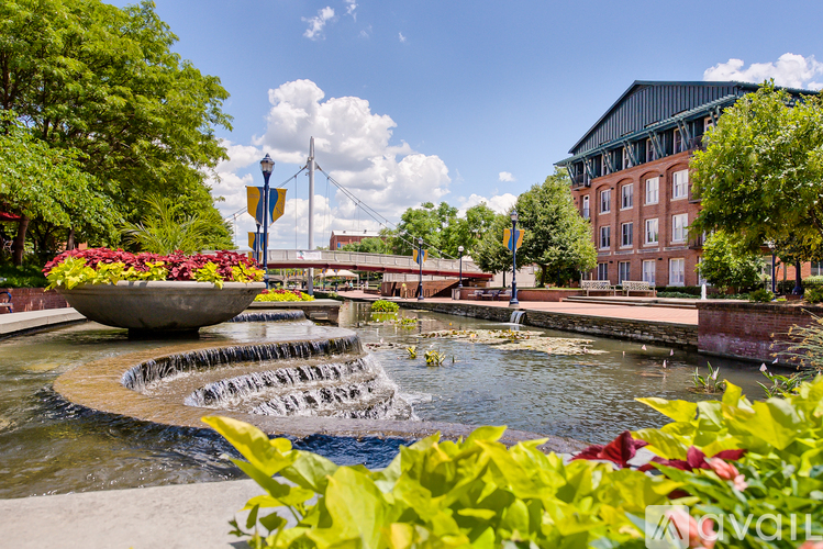 A fountain in the middle of a park with a building in the background.