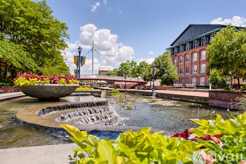 A fountain in the middle of a park with a building in the background.