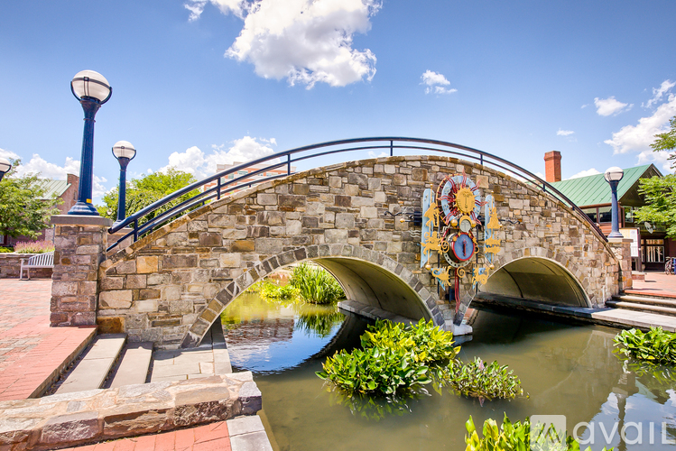 A stone bridge with a clock on it spans a body of water.