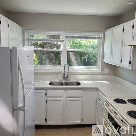A white kitchen with a sink and a window.