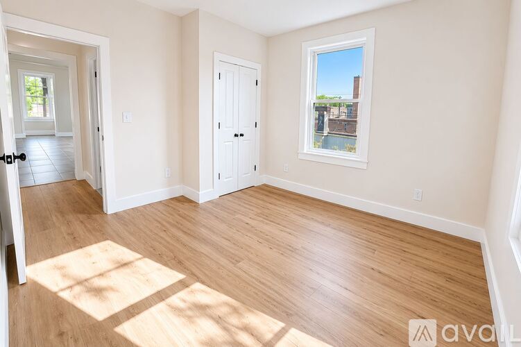 A room with wooden floors and a window showing a view of a building.