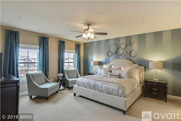 A bedroom with a large bed, two chairs, and a ceiling fan.