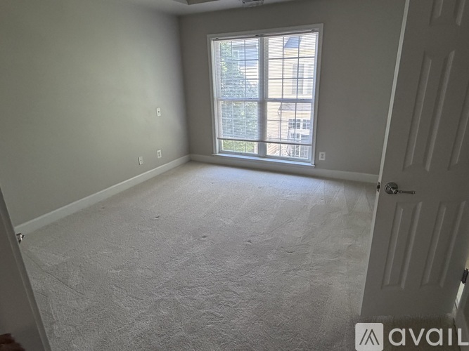 A room with a carpeted floor and a window with blinds.